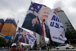 South Korean conservative activists hold huge flags with pictures of U.S. President Donald Trump as they march after a rally to welcome a planned his visit in Seoul, South Korea, Saturday, June 29, 2019.