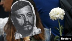 An activist holds up a picture of photojournalist Ruben Espinosa during a protest against his murder at the Angel of Independence monument in Mexico City, Mexico August 2, 2015. 