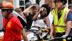 Rescue workers help an injured woman after a car ran into a large group of activists protesting a white nationalist demonstration in Charlottesville, Virginia, Saturday, Aug. 12, 2017. (AP Photo/Steve Helber)