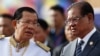 FILE - Cambodia's Prime Minister Hun Sen, left, listens to Sar Kheng, right, deputy prime minister and Minister of Ministry of Interior, as they wait to attend the Independence Day celebrations in Phnom Penh, Cambodia, Thursday, Nov. 9, 2017