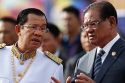 FILE - Cambodia's Prime Minister Hun Sen, left, listens to Sar Kheng, right, deputy prime minister and Minister of Ministry of Interior, as they wait to attend the Independence Day celebrations in Phnom Penh, Cambodia, Thursday, Nov. 9, 2017. (AP Photo)