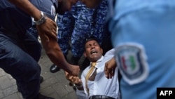 FILE - Maldives police try to move former president Mohamed Nasheed during a scuffle as he arrives at a courthouse in Male, February 23, 2015. 