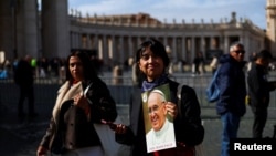 Una persona sostiene una imagen del Papa Francisco mientras continúa su hospitalización, en la Plaza de San Pedro, en el Vaticano, el 26 de febrero de 2025.