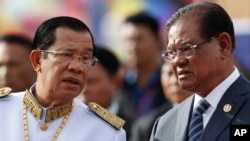 FILE - Cambodia's Prime Minister Hun Sen, left, listens to Sar Kheng, right, deputy prime minister and Minister of Ministry of Interior, as they wait to attend the Independence Day celebrations in Phnom Penh, Cambodia, Thursday, Nov. 9, 2017