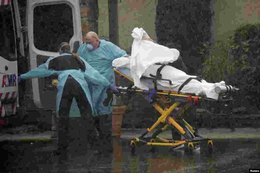 Medics transport a patient through heavy rain into an ambulance at Life Care Center of Kirkland, the long-term care facility linked to several confirmed coronavirus cases in the state, in Kirkland, Washington, March 7, 2020.