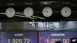 A currency trader works near the screens showing the KOSPI left, and the foreign exchange rate between U.S. dollar and South Korean won at the foreign exchange dealing room in Seoul, South Korea, May 18, 2020.