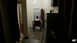 FILE - Anas al-Sarrari moves around in his wheelchair in his home in Marib, Yemen, July 29, 2018. He says he was hung by his wrists from the ceiling for 60 days and beaten while locked up in a prison run by Yemen’s Houthi rebels.