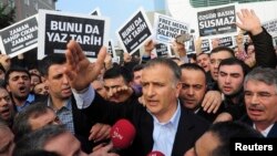 Zaman editor-in-chief Ekrem Dumanli, surrounded by his colleagues and plainclothes police officers (C), reacts as he leaves the headquarters of Zaman daily newspaper in Istanbul December 14, 2014. 