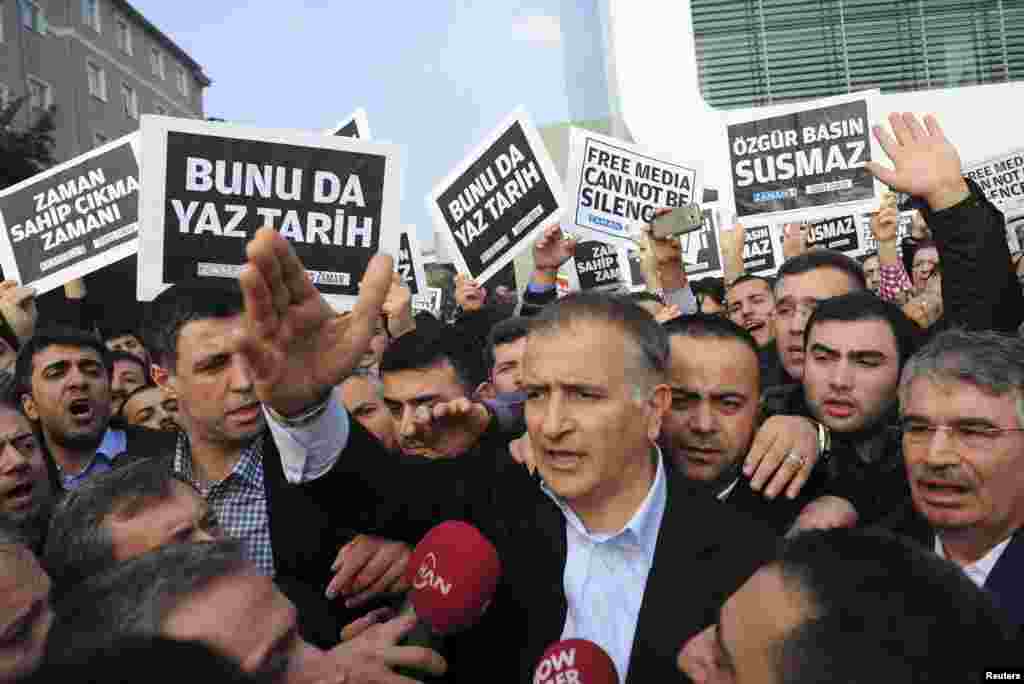 Zaman editor-in-chief Ekrem Dumanli, surrounded by his colleagues and plainclothes police officers (center), reacts as he leaves the headquarters of the Zaman daily newspaper, in Istanbul, Turkey, Dec. 14, 2014.