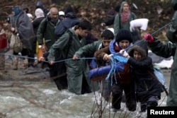 Refugees and migrants attempt to cross a river near the Greek-Macedonian border to enter Macedonia after an unsuccessful attempt yesterday, west of the village of Idomeni, Greece, March 15, 2016