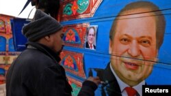 Sohail Ghuri applies the final touches to a portrait of former PM Sharif on wooden planks in the back of a truck at a workshop, in Peshawar