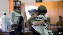 Siswa Yahudi Israel berpelukan sebelum berdoa di sinagog tempat dua dari tiga remaja Israel yang hilang belajar.