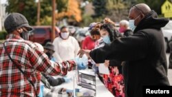 FILE - A volunteer hands out masks to protect against COVID-19 infection in Rochester, N.Y., Oct. 17, 2020.