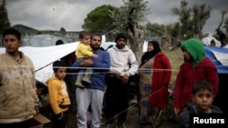 FILE - Syrian refugee Bashar Wakaa (3rd L) and his family stand in front of their tents at a makeshift camp for refugees and migrants next to the Moria camp on the island of Lesbos, Greece, Nov. 30, 2017.