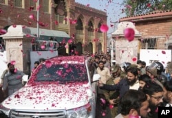 Supporters of Hafiz Saeed, head of Pakistan's Jamaat-ud-Dawa group, shower his car with rose petals as he leaves a court in Lahore, Pakistan, Nov. 21, 2017.