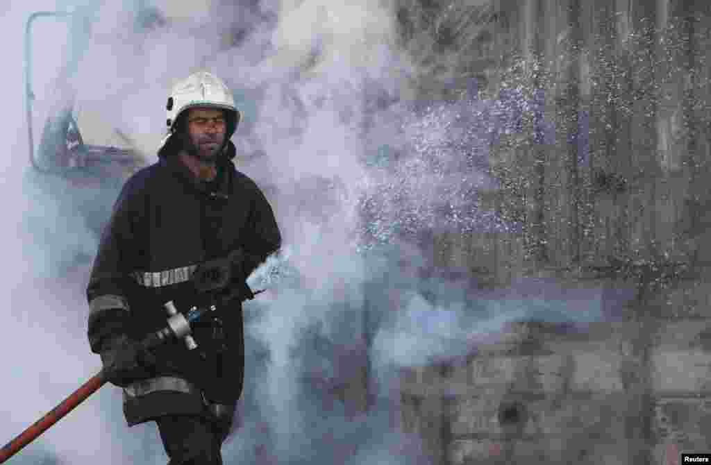 A civil defense worker puts out a fire after what activists said were explosive barrels thrown by forces loyal to President Bashar al-Assad, al-Inzarat district, Aleppo, Feb. 18, 2014.&nbsp;