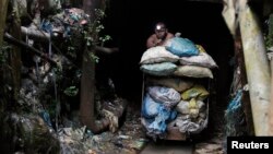 A Filipino miner pushes a cart containing sacks of mineral muck ore in the Compostela Valley, southern Philippines. May 24, 2012