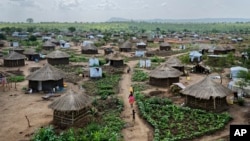 FILE - Women and children return home with containers of water, in a section of the Bidi Bidi refugee settlement in northern Uganda, June 9, 2017. The number of South Sudanese refugees sheltering in Uganda has reached 1 million, the United Nations said Thursday.