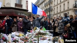 FILE - People pay tribute to victims outside Le Carillon restaurant, one of the attack sites in Paris, Nov. 16, 2015. 
