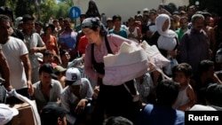 Seorang perempuan membawa bayinya di antara para migran lainnya di Pulau Kos, Yunani (18/8).