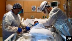 FILE - Medical personnel check on a COVID-19 patient at Providence Holy Cross Medical Center in Los Angeles, Nov. 19, 2020. With coronavirus cases surging, California Gov. Gavin Newsom announced a new stay-at-home order Dec. 3, 2020.