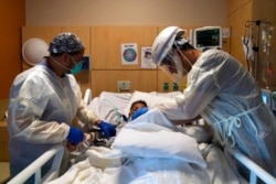 FILE - Medical personnel check on a COVID-19 patient at Providence Holy Cross Medical Center in Los Angeles, Nov. 19, 2020.