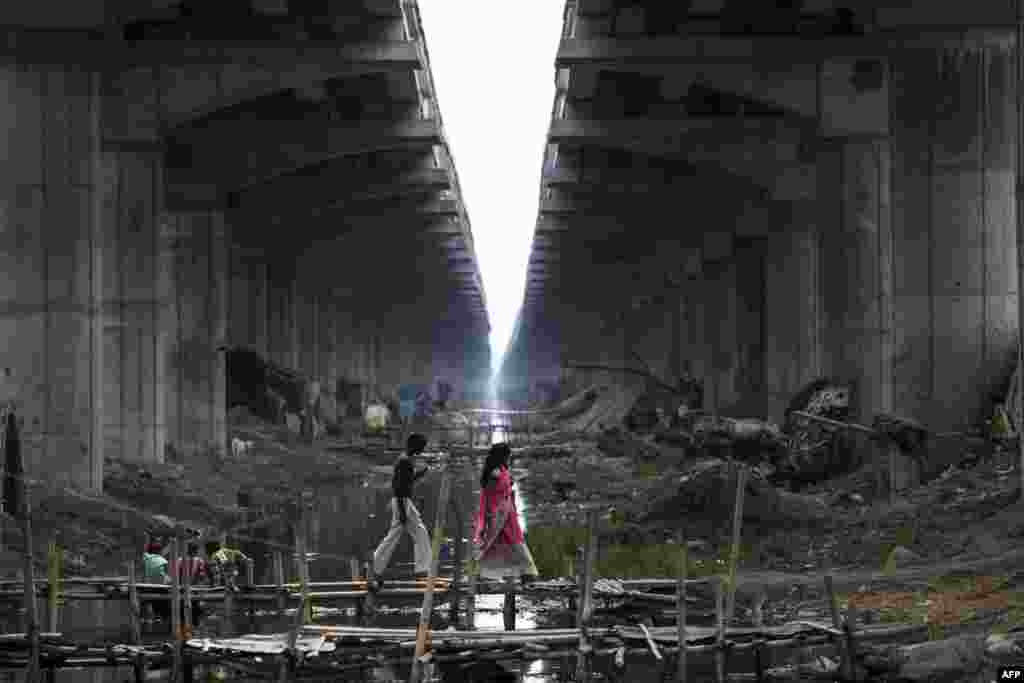 Residents walk across a makeshift bridge over a sewage canal under the Digha Bridge link road in Danapur, in the Indian state of Bihar.