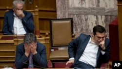 Greek Finance Minister Euclid Tsakalotos, left, and Greece's Prime Minister Alexis Tsipras react during a parliamentary session to vote more austerity measures as part of an agreement with international bailout creditors, in Athens, May 18, 2017. 
