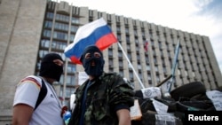 Các chiến binh ủng hộ Nga đeo mặt nạ đứng gác gần các chướng ngại vật bên ngoài tòa nhà chính phủ ở Donetsk, đông Ukraine, ngày 23/4/2014.
