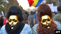 People wear golden masks during a protest in Bucharest October 20, 2013. Thousands of people marched for the eighth consecutive Sunday in Romania against a Canadian gold mine plan to extract 300 tons of gold and 1,600 tons of silver over 16 years from Rosia Montana, in north-western Romania, and against the extraction of shale gas, calling for Prime Minister Victor Ponta's resignation. 