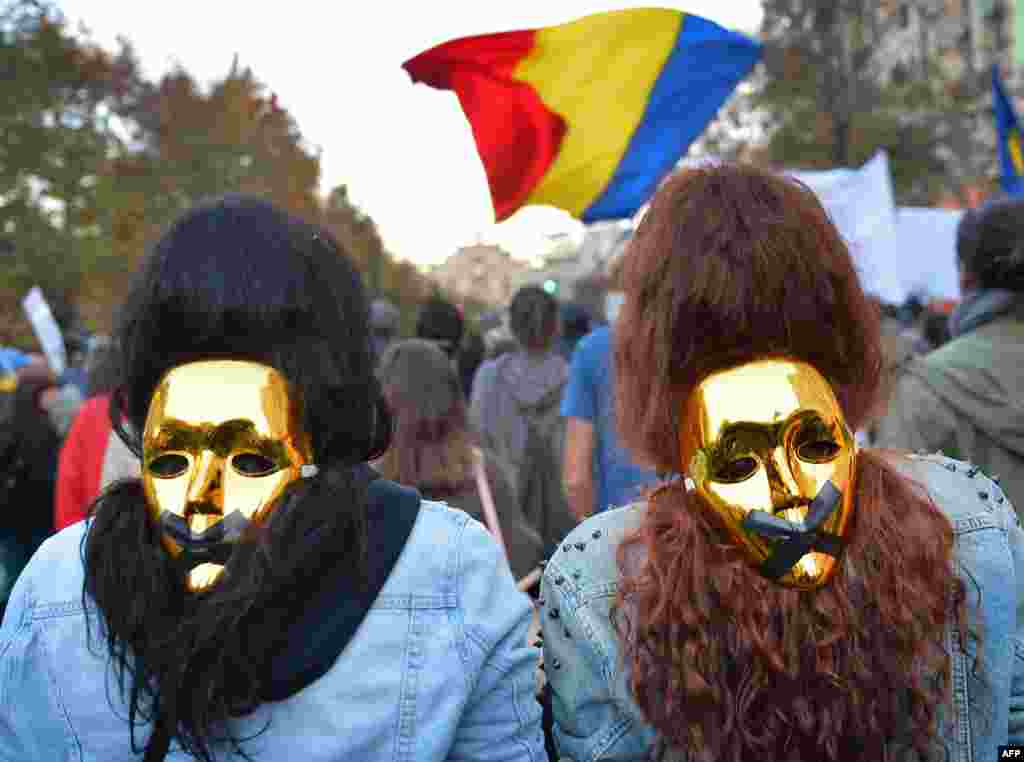 People wear golden masks during a protest in Bucharest, Romania. Thousands of people marched for the eighth week against a Canadian gold mine plan to extract 300 tons of gold and 1,600 tons of silver over 16 years, Oct. 20, 2013.