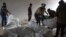 Residents and a rescuer from the Syrian White Helmets pile up bodies of civilians killed in a Syrian government bombardment in the town of Qawqafeen in the rebel-held Idlib province on Nov. 25, 2023.
