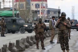 Afghan security personnel stand guard near the site of an attack to a Sikh temple in Kabul on March 25, 2020.