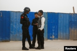 A police officer talks to men in a street in Kashgar, Xinjiang Uighur Autonomous Region, China, March 24, 2017.