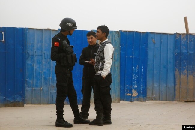 A police officer talks to men in a street in Kashgar, Xinjiang Uighur Autonomous Region, China, March 24, 2017.
