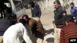 Pakistani policemen move the body of a colleague into an ambulance following an attack by gunmen on a polio security team in Dera Ismail Khan on March 11, 2014. Two policemen guarding a polio vaccination team in northwest Pakistan were were shot dead by a