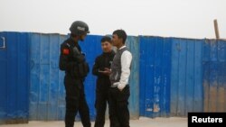 FILE - A police officer talks to men in a street in Kashgar, Xinjiang Uighur Autonomous Region, China, March 24, 2017. 