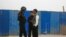 FILE - A police officer talks to men in a street in Kashgar, Xinjiang Uighur Autonomous Region, China, March 24, 2017. 