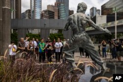 Para penggemar berkumpul di depan patung Bruce Lee pada peringatan 50 tahun kematiannya di Hong Kong, Kamis, 20 Juli 2023. (AP Photo/Louise Delmotte)