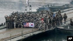 FILE - U.S. and South Korean army soldiers pose on a floating bridge on the Hantan river after a river crossing operation, part of an annual joint military exercise between South Korea and the United States in Yeoncheon, South Korea, Dec. 10, 2015.