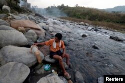 FILE - A man, who lost his calf in a landmine explosion, puts on his prosthesis after washing himself by a river on Jan. 31, 2013.