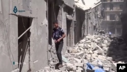 Warga bergegas melewati reruntuhan bangunan akibat serangan udara di Aleppo, Suriah (29/4).