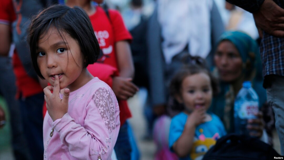 Seorang anak perempuan bersama para pengungsi lainnya menunggu di perbatasan Kroasia-Serbia dekat Sid, Serbia (16/9).