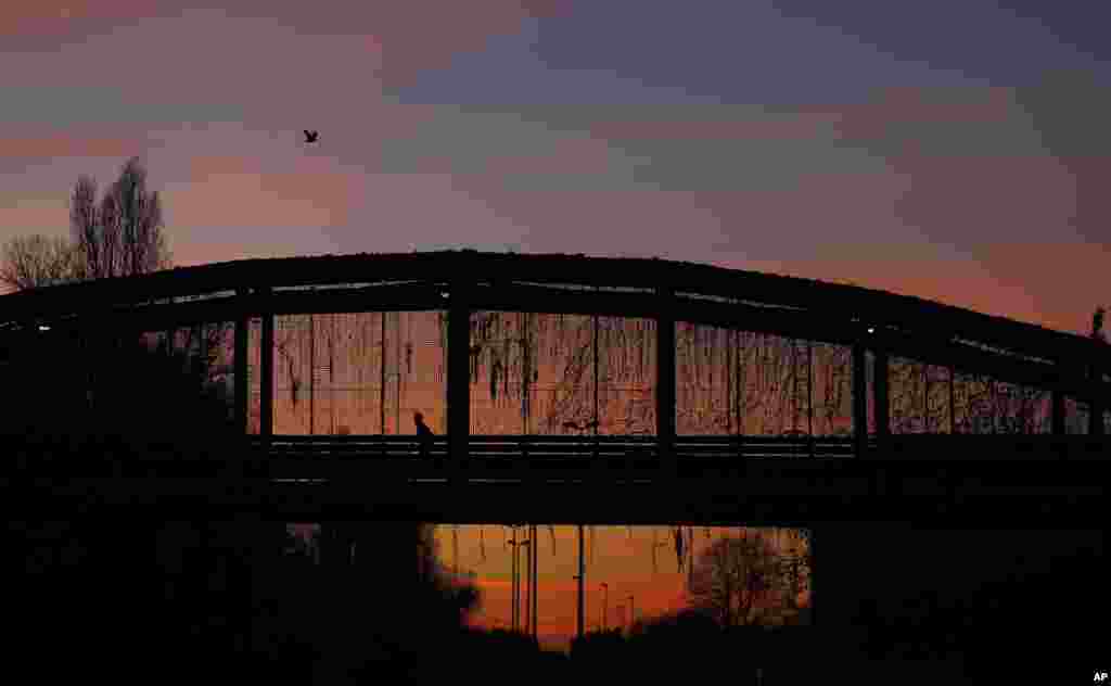 Seorang pria berolahraga lari melewati jembatan &quot;Parco Nord&quot; saat matahari terbenam di Milan, Italia.