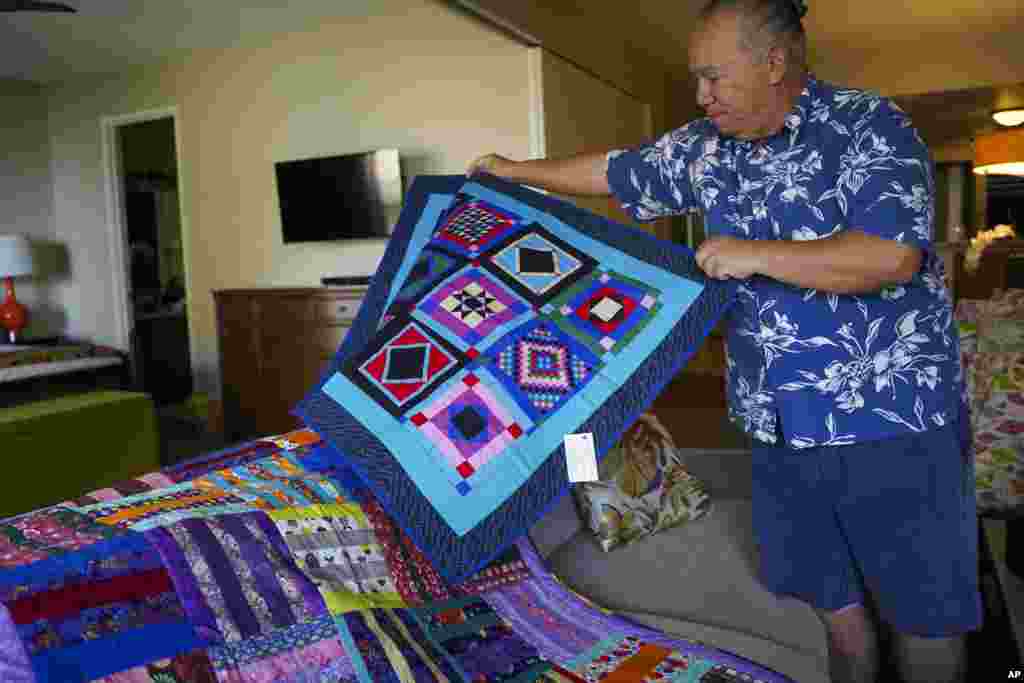 Charles Nahale lays the quilts gifted by his clients after the wildfire on Oct. 10, 2023, in Lahaina, Hawaii.&nbsp;