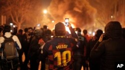 A man takes photos of fires that burn toward the end of a Catalan pro-independence protest outside the Camp Nou stadium in Barcelona, Spain, Dec. 18, 2019.