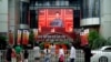 FILE - People watch a giant screen broadcasting Chinese President Xi Jinping's speech at the celebration marking the 100th founding anniversary of the Communist Party of China, in Shanghai, China, July 1, 2021.