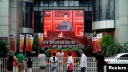 FILE - People watch a giant screen broadcasting Chinese President Xi Jinping's speech at the celebration marking the 100th founding anniversary of the Communist Party of China, in Shanghai, China, July 1, 2021.