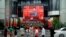 FILE - People watch a giant screen broadcasting Chinese President Xi Jinping's speech at the celebration marking the 100th founding anniversary of the Communist Party of China, in Shanghai, China, July 1, 2021.