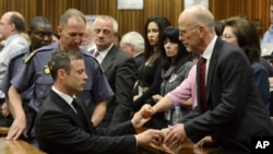 FILE - Oscar Pistorius, left front, greets his uncle Arnold Pistorius, right, and other family members as he is led out of court in Pretoria, South Africa, Oct. 21, 2014. 